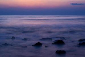 ondas suaves em uma praia rochosa à noite foto