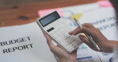 close-up mulher de negócios usando calculadora para fazer finanças matemáticas na mesa de madeira no escritório e fundo de trabalho de negócios, impostos, contabilidade, estatística e conceito de pesquisa analítica foto