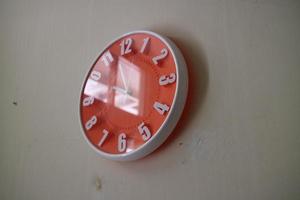 relógio de parede laranja redondo com ponteiros indicando 10 da manhã foto