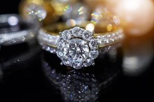anéis de diamante de joias com reflexo no fundo preto foto
