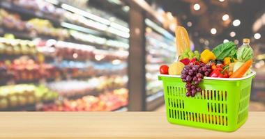 cesta de compras cheia de frutas e legumes na mesa de madeira com supermercado desfocado fundo desfocado com luz bokeh foto