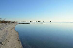 um lago ou rio com gramíneas marrons e costa com areia foto