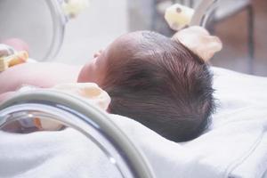 menina recém-nascida dentro da incubadora na sala de parto do hospital foto