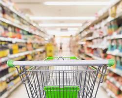 carrinho de compras vazio com interior de corredor de prateleiras de supermercado desfocar fundo desfocado foto