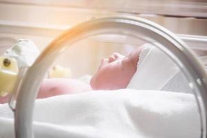 menina recém-nascida dentro da incubadora na sala de parto do hospital foto