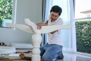 homem asiático montando móveis de mesa branca em casa foto