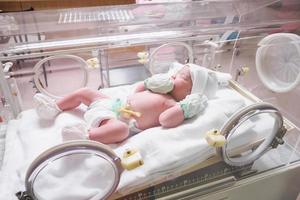 menina recém-nascida dentro da incubadora na sala de parto do hospital foto