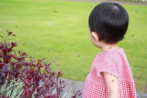 linda menina asiática tem erupção cutânea e alergia por picada de mosquito e chupando sangue enquanto brinca ao ar livre foto