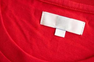 etiqueta de etiqueta de roupa em branco branca no novo fundo de textura de tecido de camisa de algodão vermelho foto