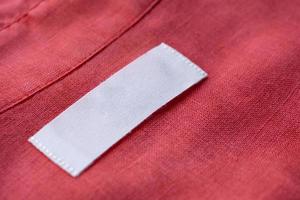 etiqueta de etiqueta de roupa em branco branca no fundo de textura de tecido de camisa de linho vermelho foto