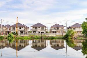 reflexão de construção de casa nova com água no lago no canteiro de obras residenciais com nuvens e céu azul foto