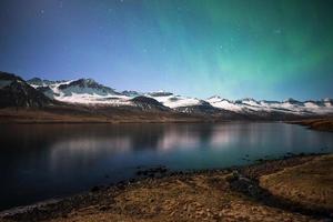a bela aurora boreal sobre o fiorde das montanhas em stoovarfjorour do leste da islândia. foto