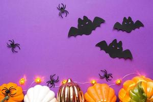 fundos de halloween de abóboras brancas, laranja e douradas, aranhas e morcegos pretos em um fundo roxo com teias de aranha e cenário terrível. horror e um feriado assustador com espaço de cópia foto