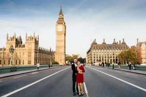 bela cidade e pessoas. jovem casal de família fica na ponte de westminster em segundo plano com big ben, aproveita o tempo livre juntos em londres, tem bons relacionamentos. fundo de paisagem da cidade. foto