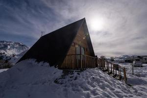uma casa de madeira cercada por neve. uma área de lazer nas montanhas foto
