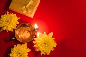 feliz Diwali. lâmpada de óleo diya, flores e caixas de presente em fundo vermelho. celebrando o tradicional festival indiano da luz. foto