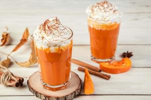 café com leite de abóbora com chantilly na luz de fundo de madeira. smoothie picante quente. bebida vegetal vegana. foto