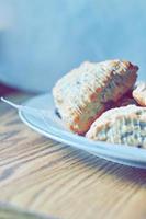 scones de mirtilo servidos em um prato branco sobre uma mesa de madeira, retratado em tons modernos. foto