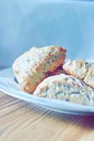 scones de mirtilo servidos em um prato branco sobre uma mesa de madeira, retratado em tons modernos. foto