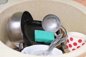 pratos sujos e utensílios de cozinha em uma pia. cozinha bagunçada. pia bagunçada. rotina diária, tarefas e tarefas domésticas. fechar-se foto