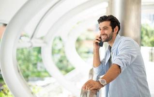 o jovem usando um smartphone para conversar com seu amigo ao ar livre. o homem vestindo pano casual e sentindo-se feliz e relaxante. foto