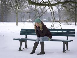 mulher sentada sozinha no banco do parque no inverno foto