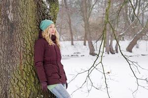 mulher pensativa encostada na árvore no inverno foto