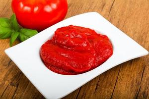 pasta de tomate em uma tigela sobre fundo de madeira foto