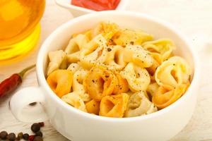 macarrão ravioli em uma tigela sobre fundo de madeira foto