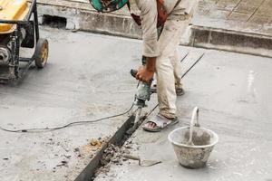 trabalhador da construção civil usando a superfície de concreto de perfuração de britadeira foto
