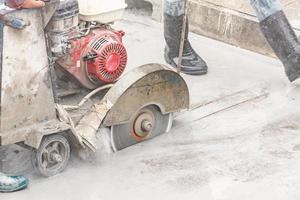 trabalhador usando máquina de lâmina de serra de diamante cortando estrada de concreto no canteiro de obras foto