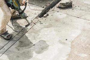 trabalhador da construção civil usando a superfície de concreto de perfuração de britadeira foto