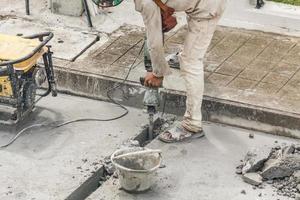 trabalhador da construção civil usando a superfície de concreto de perfuração de britadeira foto