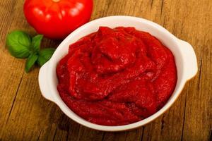 pasta de tomate em uma tigela sobre fundo de madeira foto