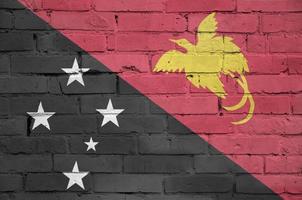 a bandeira de papua nova guiné é pintada em uma velha parede de tijolos foto