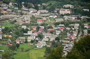 uma bela vista da vila de mezhgorye, região dos cárpatos. muitos edifícios residenciais cercados por altas montanhas da floresta e longo rio foto