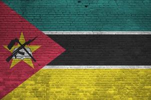 bandeira de moçambique retratada em cores de tinta na parede de tijolos antigos. banner texturizado em fundo de alvenaria de parede de tijolo grande foto