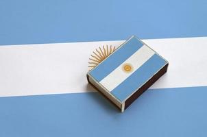 bandeira argentina é retratada em uma caixa de fósforos que fica em uma grande bandeira foto