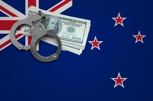 bandeira da nova zelândia com algemas e um pacote de dólares. o conceito de quebrar a lei e crimes de ladrões foto