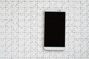 um grande smartphone moderno com tela sensível ao toque encontra-se em um quebra-cabeça branco em estado montado foto