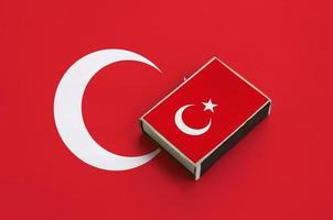 a bandeira da turquia é retratada em uma caixa de fósforos que fica em uma grande bandeira foto