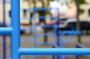 tubos de metal azul e barras transversais contra um campo de esportes de rua para treinamento de atletismo. equipamento de ginástica esportiva ao ar livre. foto macro com foco seletivo e fundo extremamente desfocado