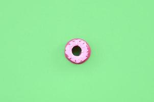 único pequeno donut de plástico encontra-se em um fundo colorido pastel. composição mínima plana leiga. vista do topo. foto