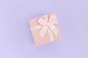 pequena caixa de presente rosa com fita encontra-se em um fundo violeta. vista superior plana do minimalismo foto