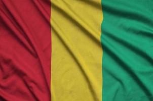 a bandeira da guiné é retratada em um tecido esportivo com muitas dobras. bandeira da equipe esportiva foto