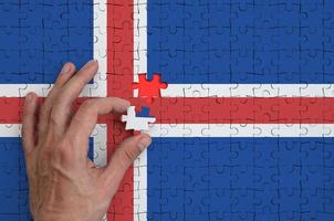 bandeira da Islândia é retratada em um quebra-cabeça, que a mão do homem completa para dobrar foto