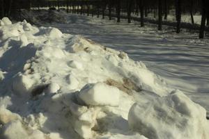 neve removida da estrada. pilha de neve lá fora. estrada suja. foto