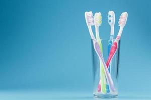 escovas de dentes coloridas em um copo sobre um fundo azul. foto