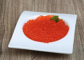 caviar vermelho em uma tigela sobre fundo de madeira foto