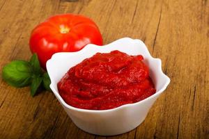 pasta de tomate em uma tigela sobre fundo de madeira foto